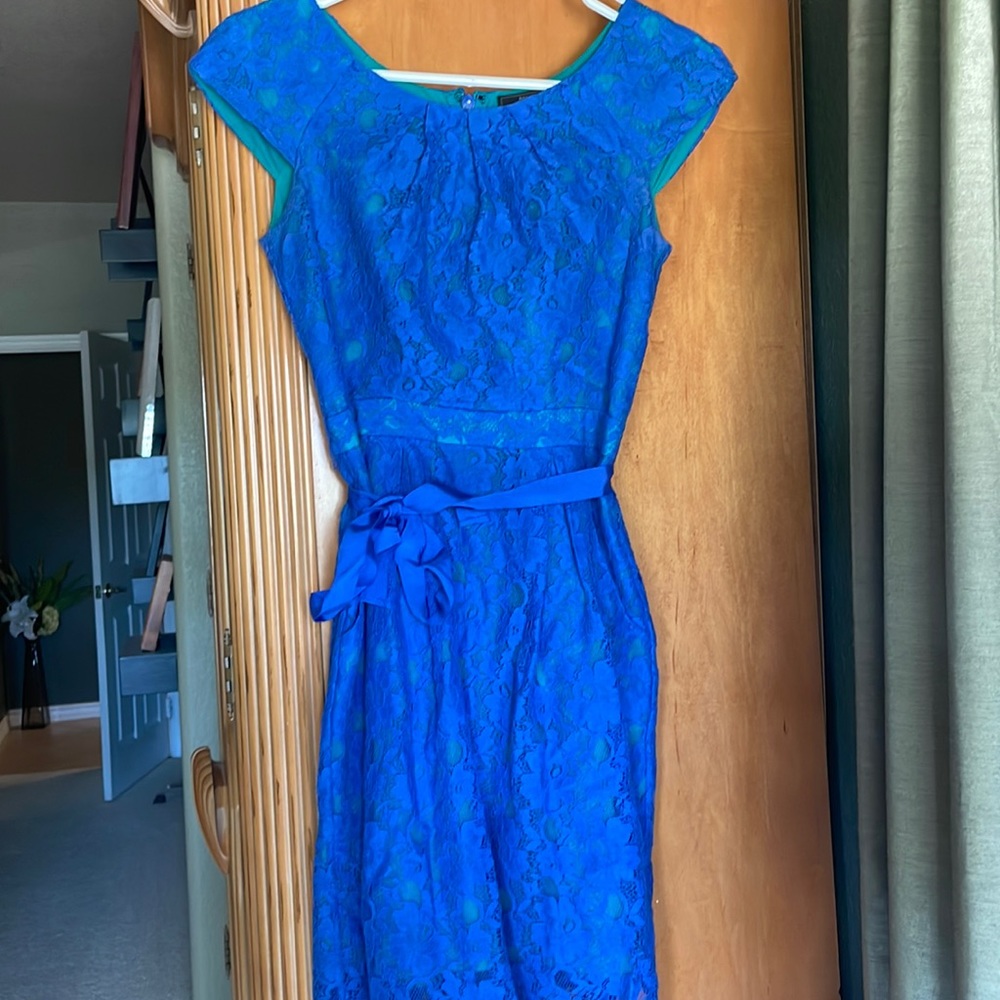 Turquoise dress with vibrant blue floral lace covering and matching ribbon.